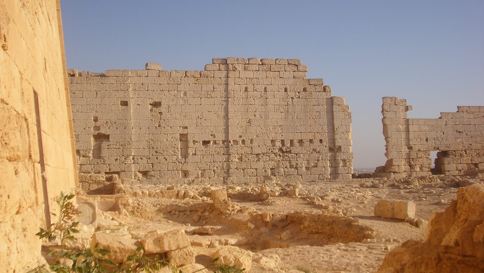 داخل سور معبد أوزوريس في تابوزيريس ماجنا: الجدار الجنوبي من الحجر الجيري وبوابته، وأساسات محفورة في المقدمة